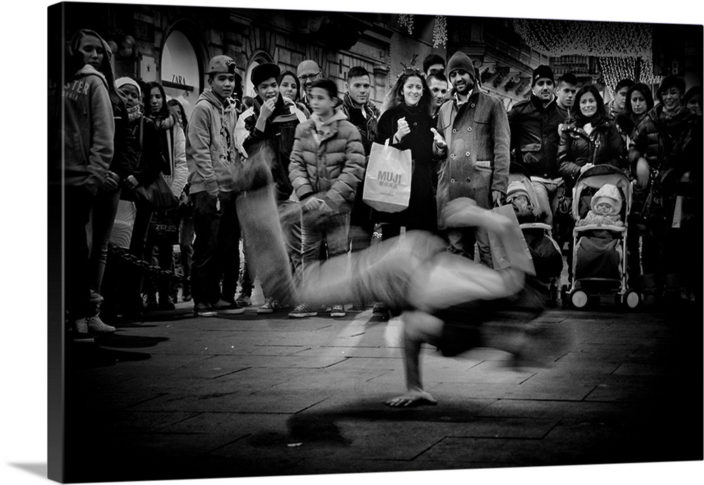 A crowd of people gathering to watch a breakdancer perform in the street.