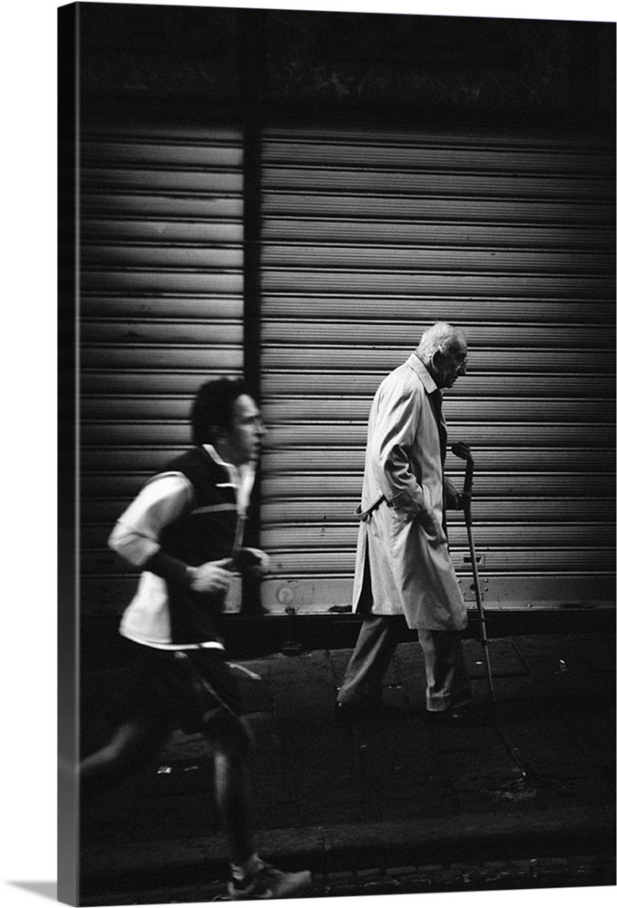 A young man jogs past an elderly man walking with a cane in the city, showing the contrast in their ages.