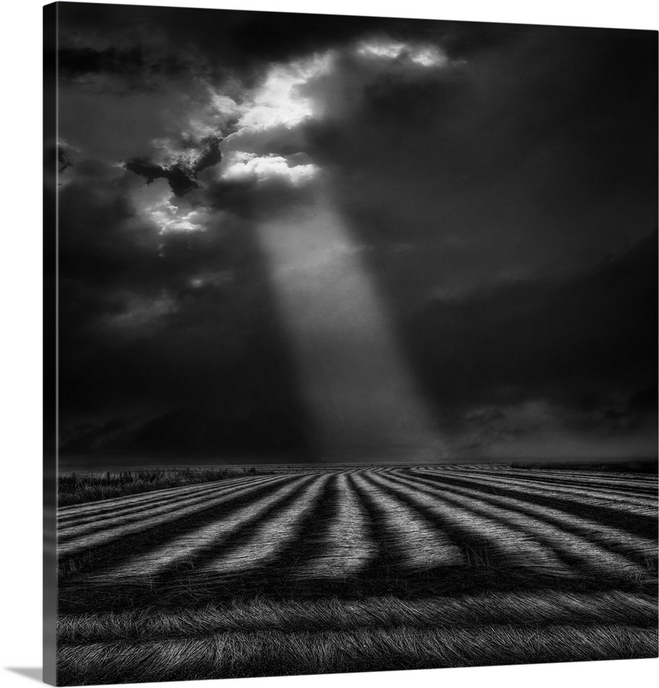 A shaft of sunlight shines down dark clouds over a countryside scene.