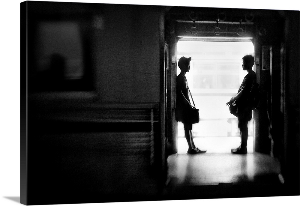 Two people with luggage wait in the doorway for their train, Jakarta, Indonesia.