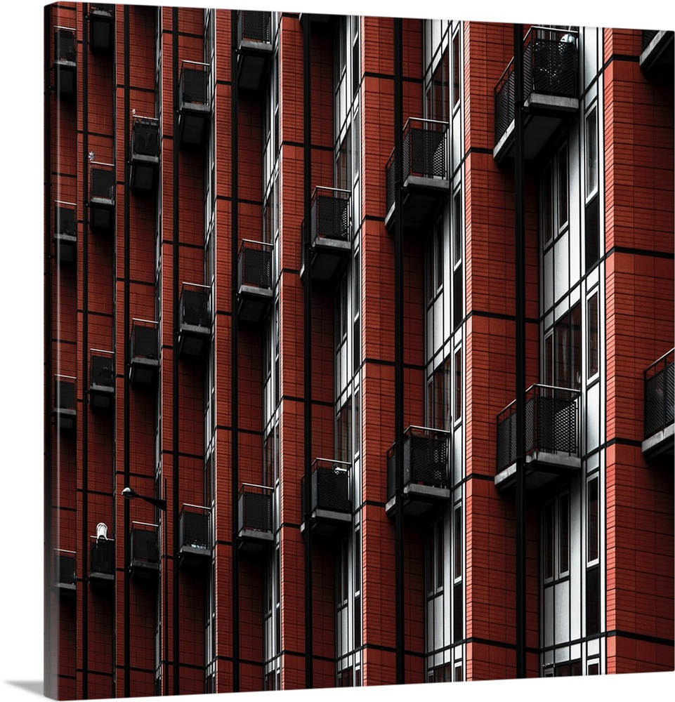 Repeating pattern of balconies and red walls on an apartment building.