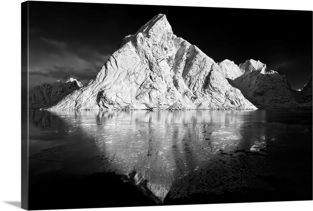 Black and white image of a large white mountain rising from the ocean.
