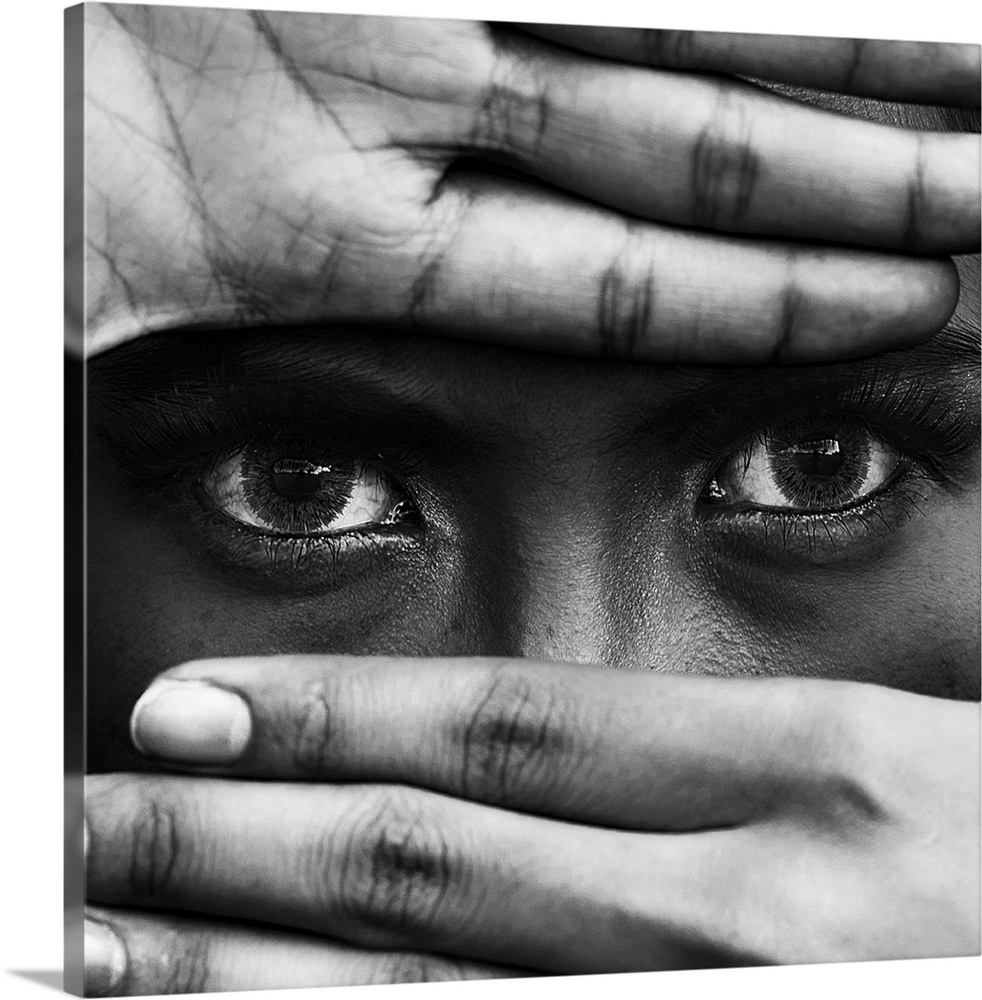 A black and white portrait of a close-up of hands covering a persons leaving the eyes exposed.