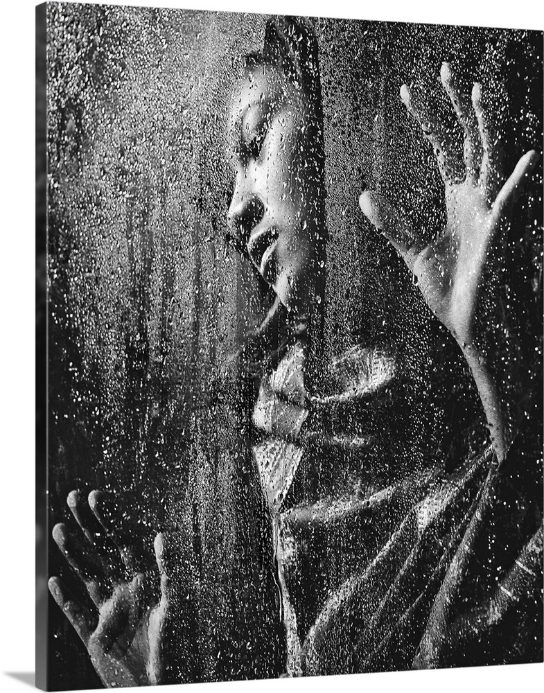 A woman pressing her hands against a window covered in raindrops.