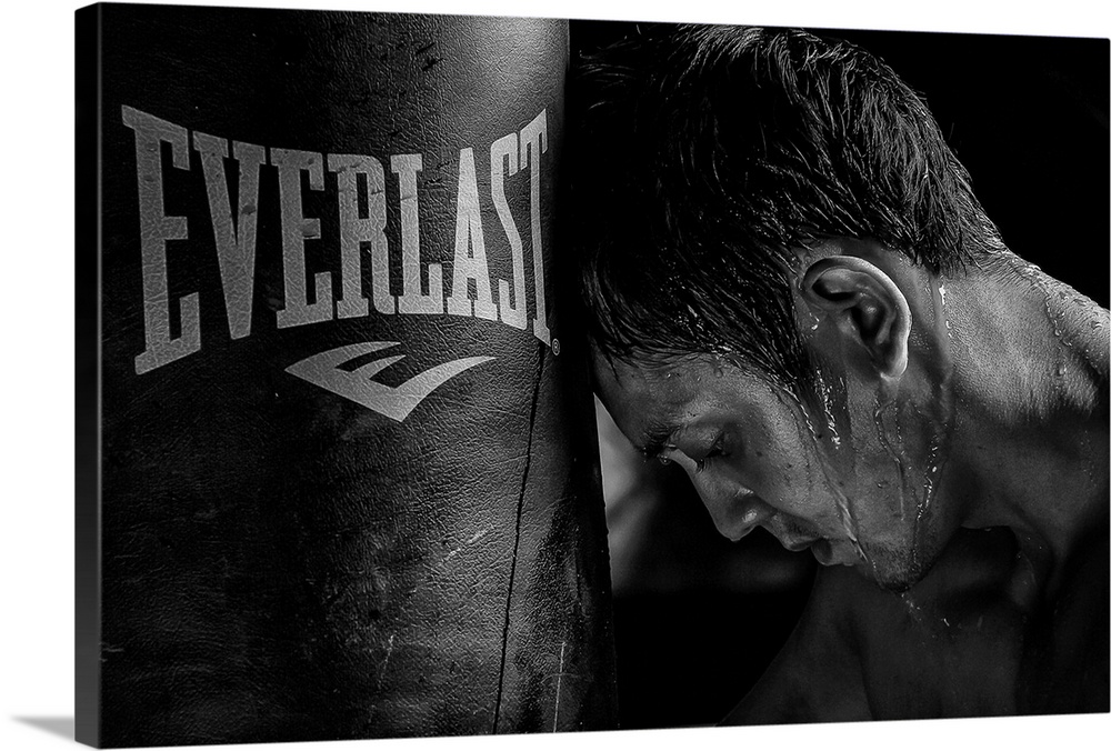 A tire boxer rests his head against his punching bag.
