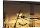 image thumbnail of Silhouette of people working on a large electrical pylon with the sun setting in the background.