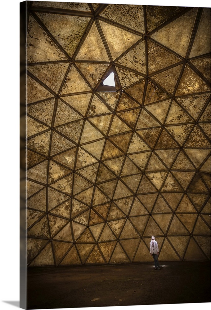 A person standing in a spotlight created by one open panel in a geodesic dome structure.