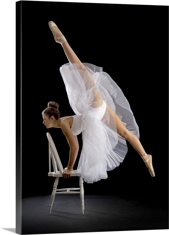 A ballerina posing on a chair with one leg high in the air.