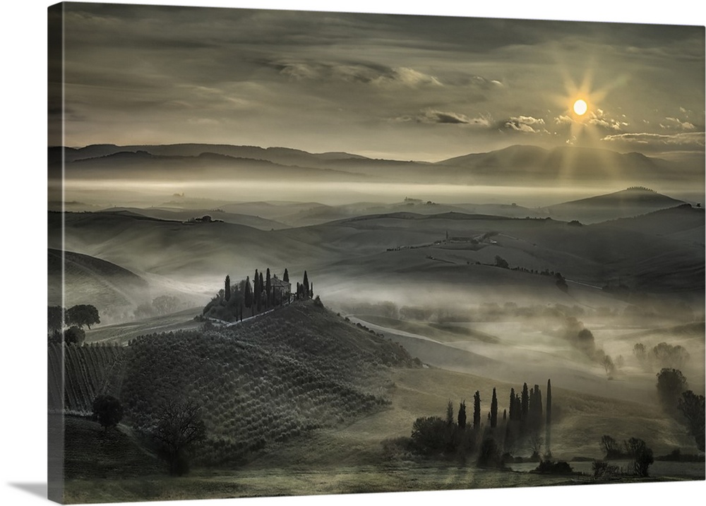The Tuscan countryside under a blanket of fog on a cloudy morning.