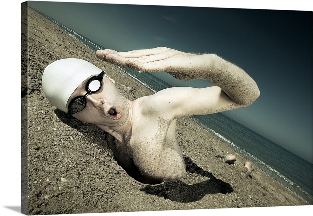 A swimmer with a cap and goggles attempting to swim in the sand.