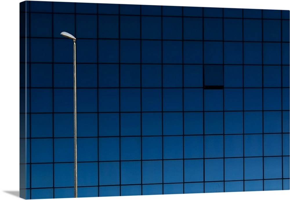 A white streetlamp breaking up the pattern of blue windows in a building.