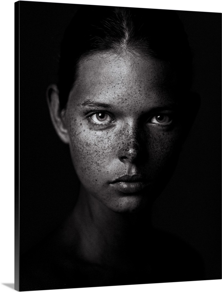 Black and white portrait of a young woman with a freckled visage and a stern expression.