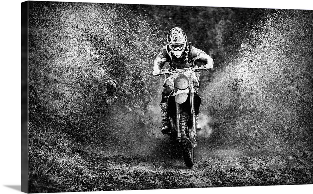 Motorcyclist riding his bike through a mud puddle, creating a huge splash.