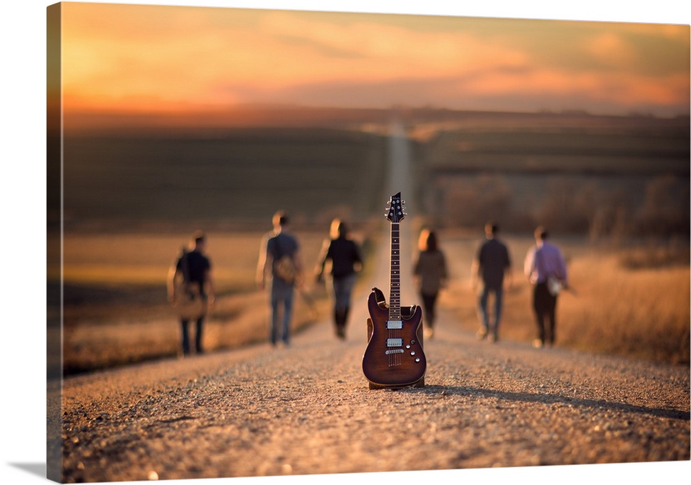 A group of musicians walk down a gravel road, with an electric guitar in the foreground.