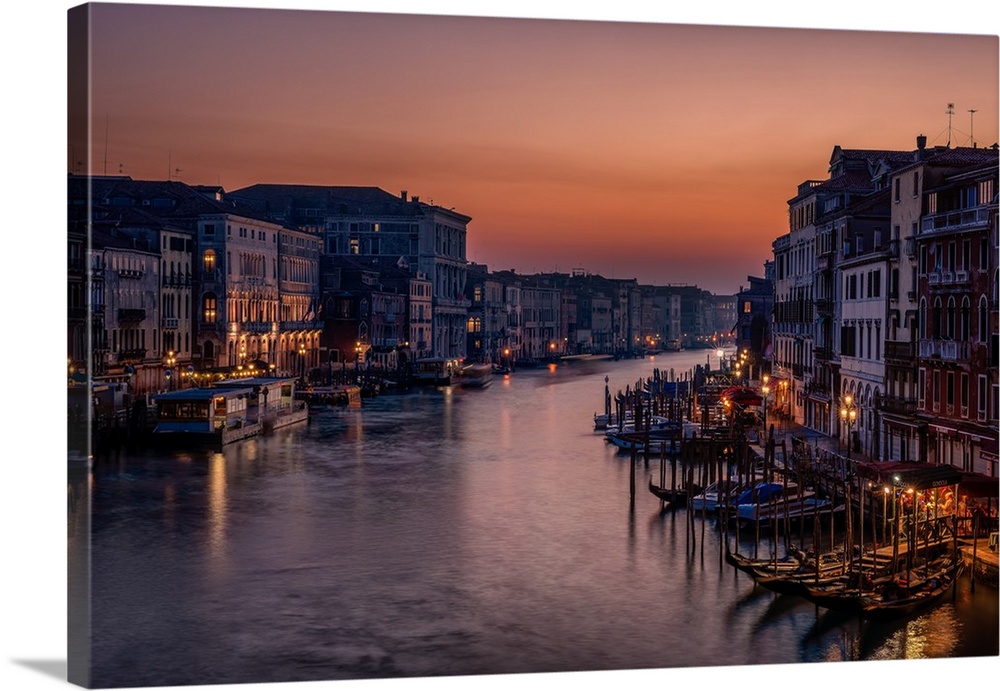 Lights in the city of Venice surrounding the canal at twilight.