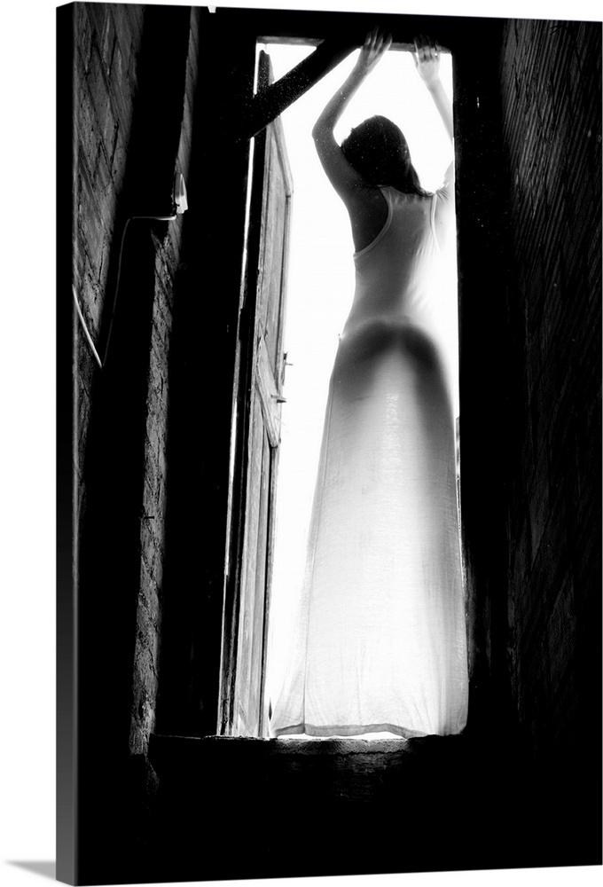 Black and white portrait of a woman standing in a doorway with light shining in.