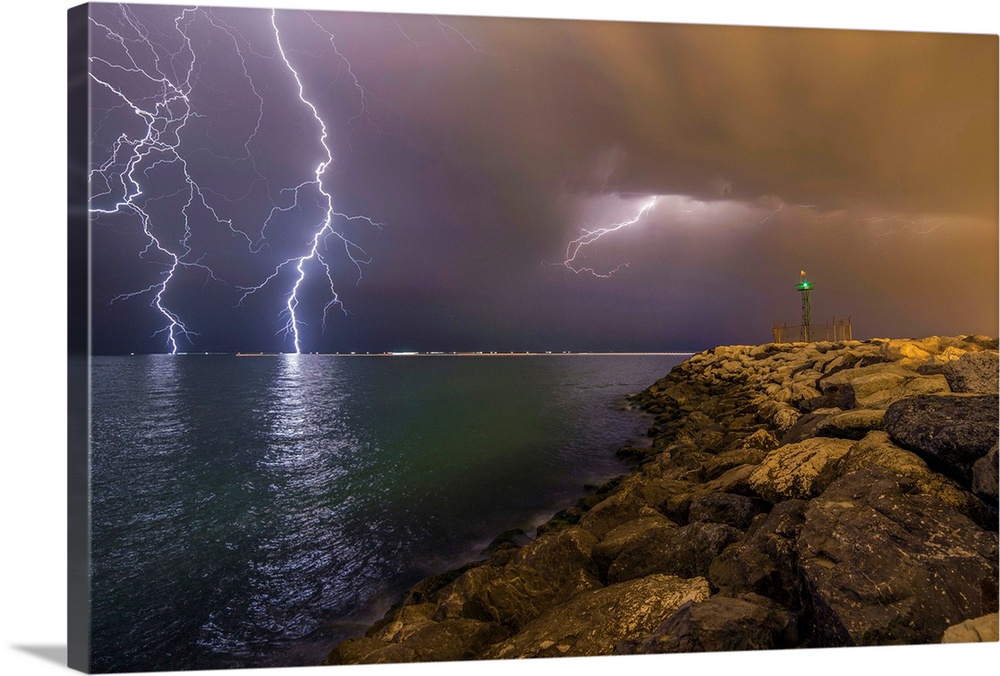 An intense photograph of a coastal scene with multiple lightning strikes hitting the ocean.