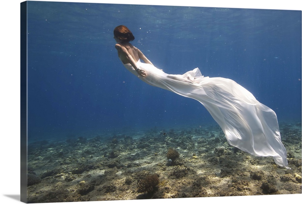 Woman in a flowing white dress swimming underwater.