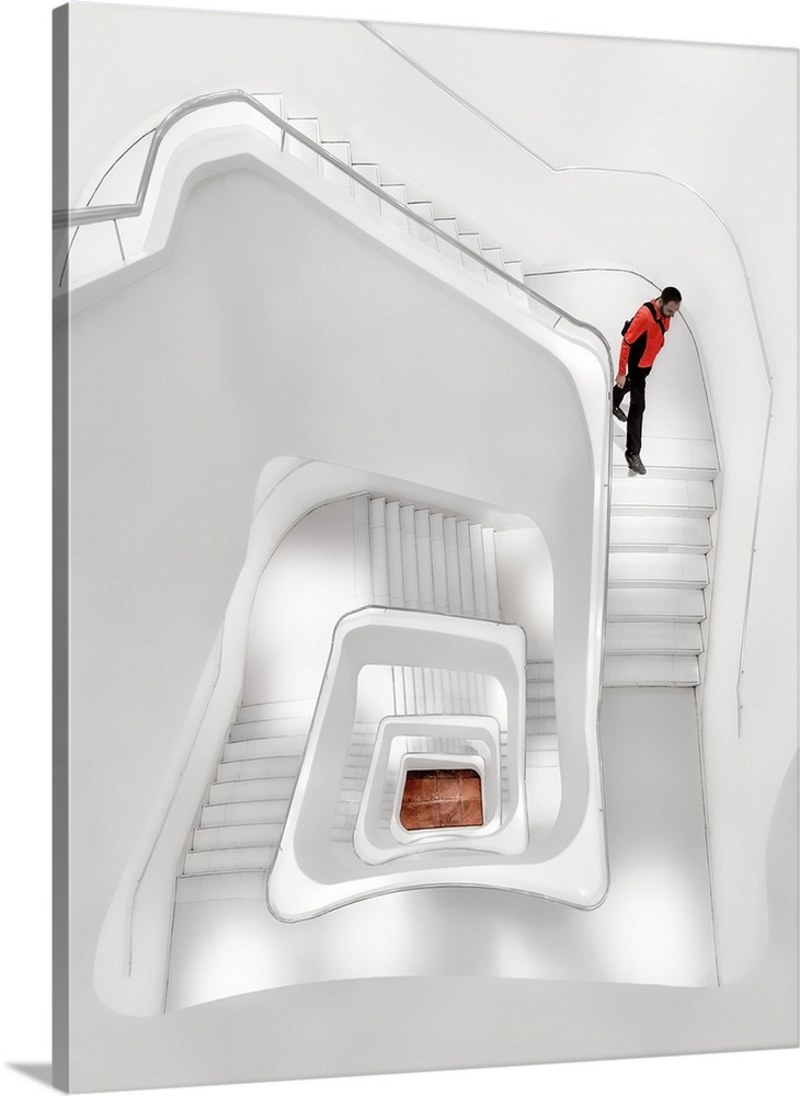 A man walking down an all-white spiral staircase in Madrid, Spain.