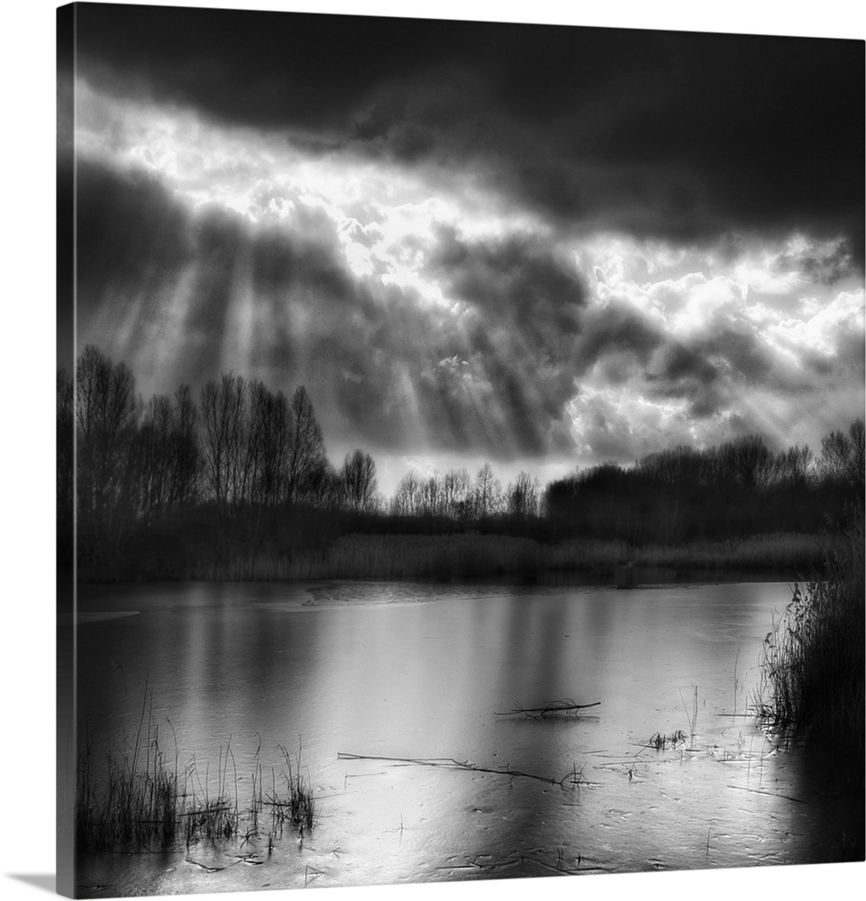 Sunbeams shining through the clouds over a lake in Belgium in the winter.