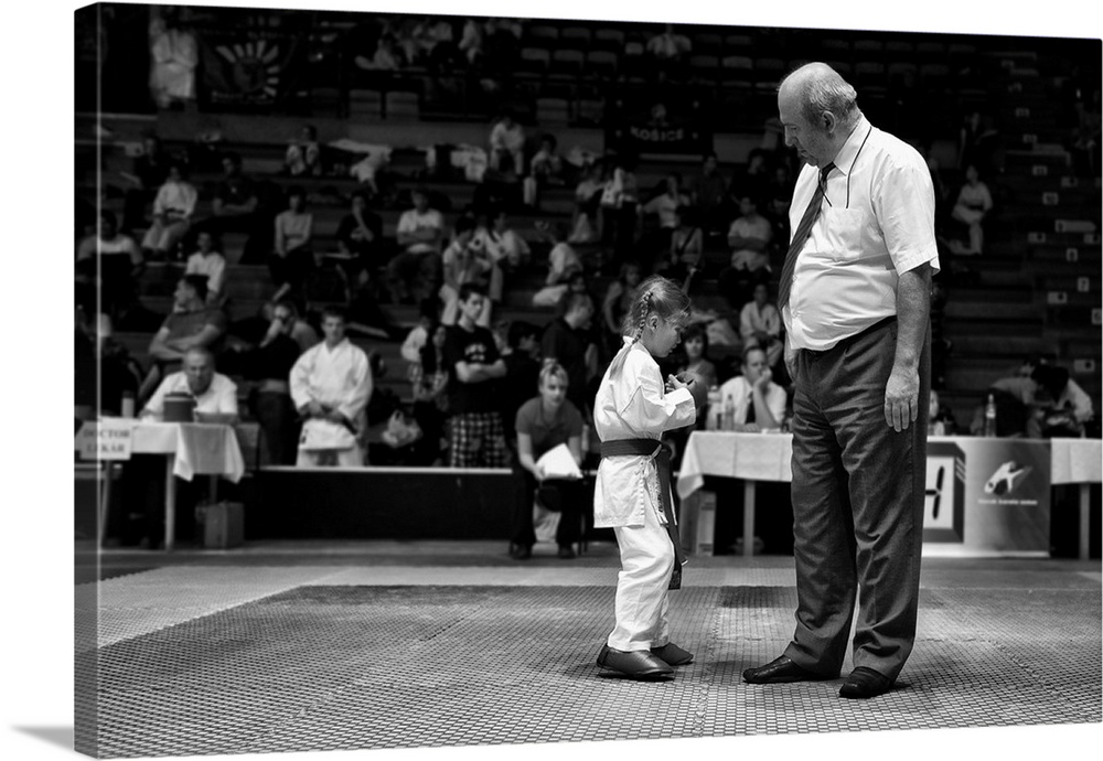 A small girl shows off her karate abilities to a judge.