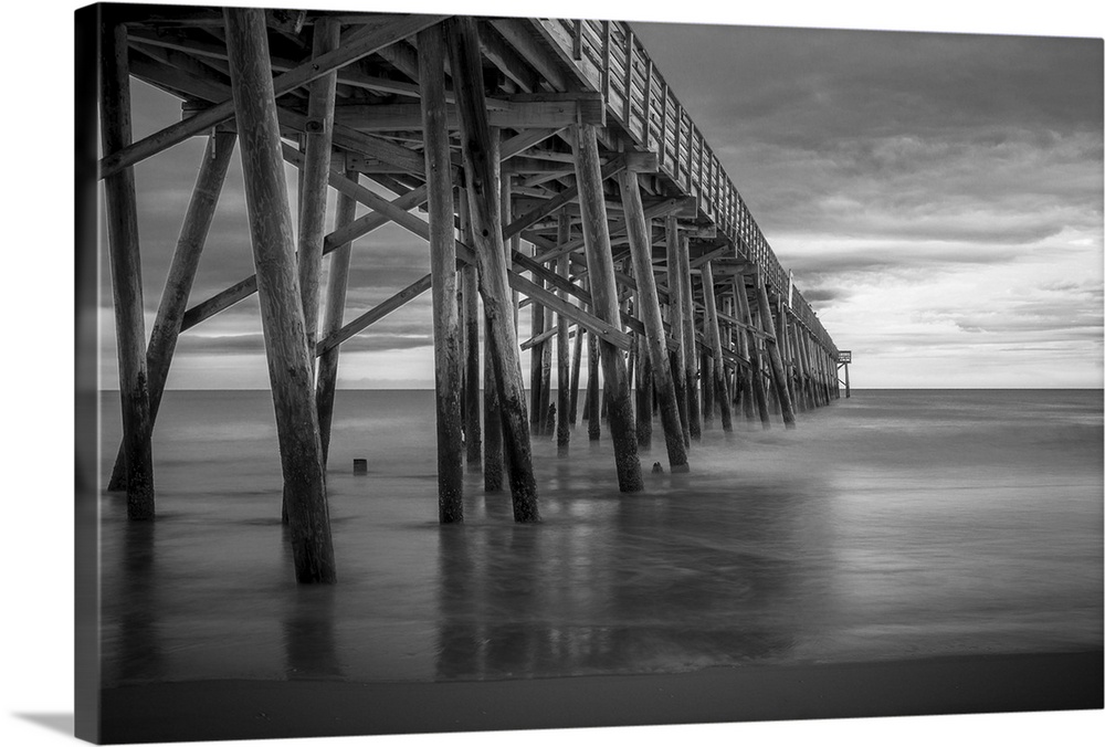 A black and white photograph of a long pier jetting out over the ocean.