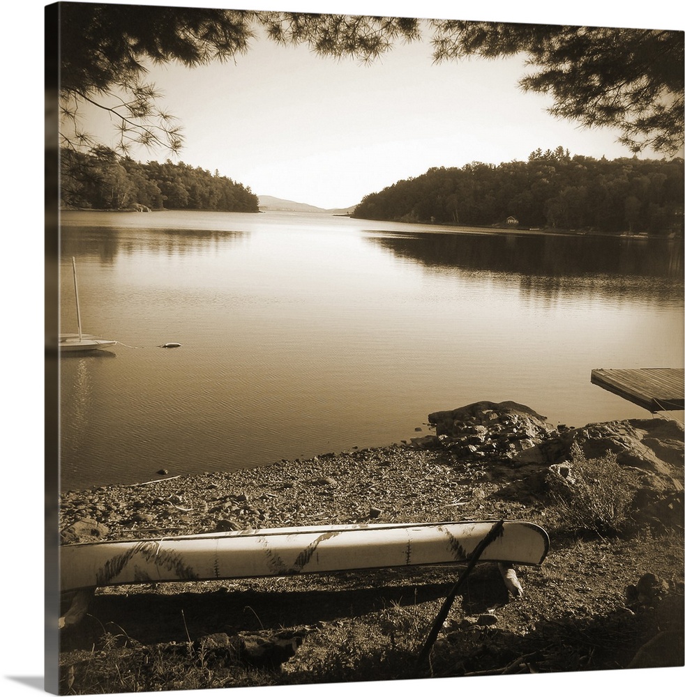 Sepia toned photograph of a canoe resting on the shores of a lake in an idyllic wilderness scene.