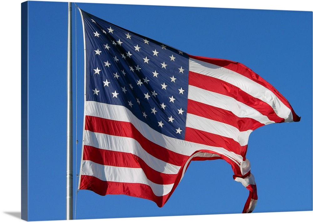A furled American flag waving during a blue sky day