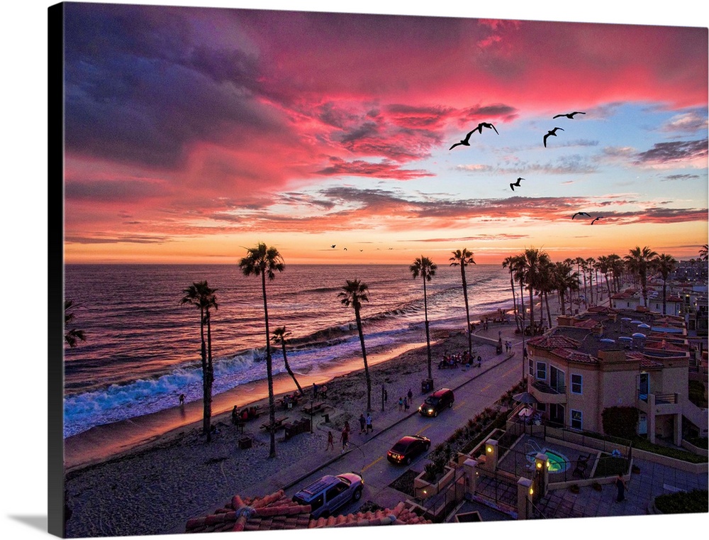 Colorful sunset with seabirds passing over the coastline in Oceanside, California, USA.