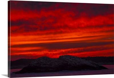 A Blazing Red Sky At Sunset Silhouettes Commorant Seabirds On A Rocky Island