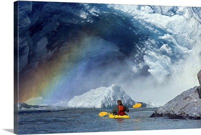 A kayaker explores a melt stream gushing from beneath Mendenhall Glacier