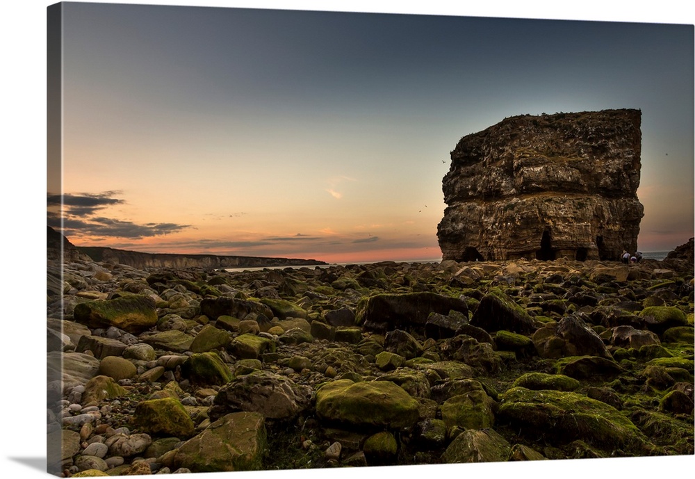 A large rock at the water's edge with moss covered rocks on the ground, south shields, Tyne and Wear, England.