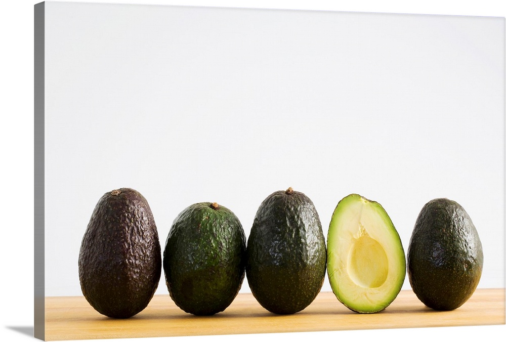 A Row Of Avocados With Interior Of One Showing Standing Upright