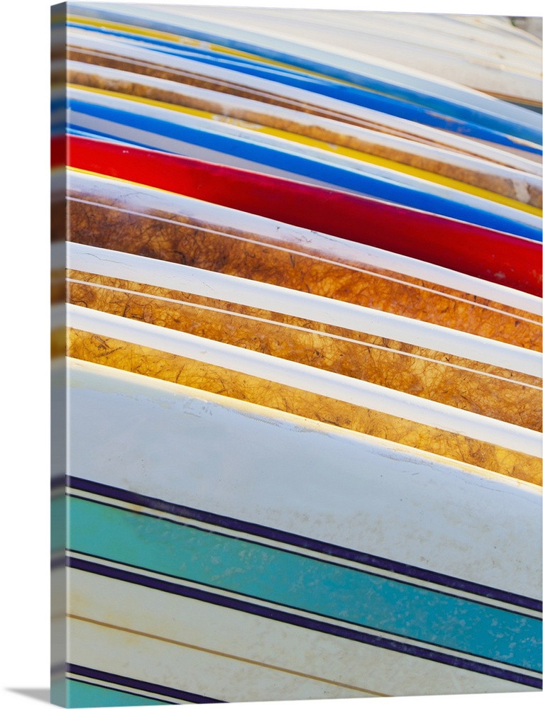 A stack of colorful longboard surfboards placed on the beach; Waikiki