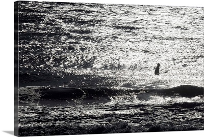 A surfer sits alone out in the waves.