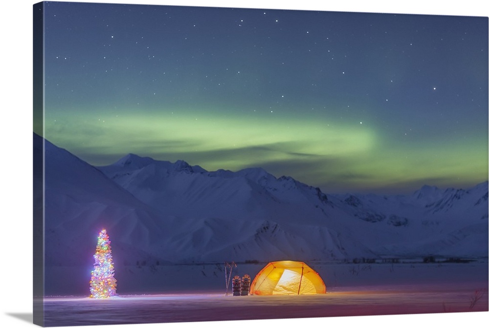 A tent and decorated Christmas tree glow under the Northern Lights