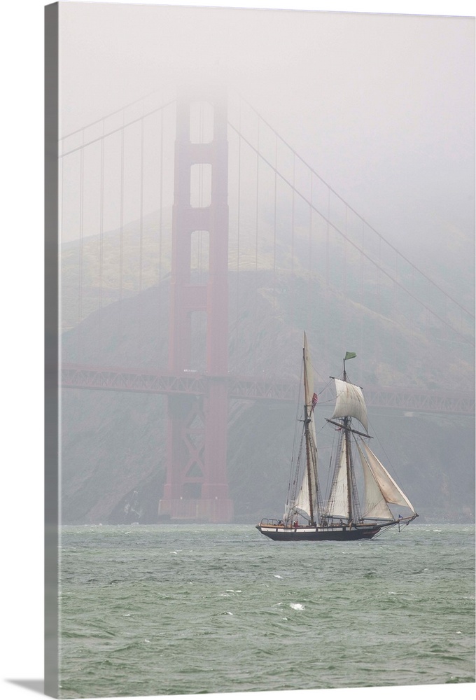 A two masted schooner sails under the Golden Gate Bridge.