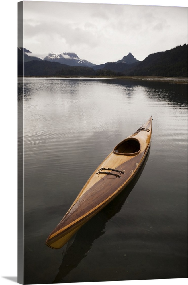 A Wooden Kayak Sits On Tranquil Water With A View Of The Mountains In The Background, Kachemak Bay State Park; Alaska, Uni...