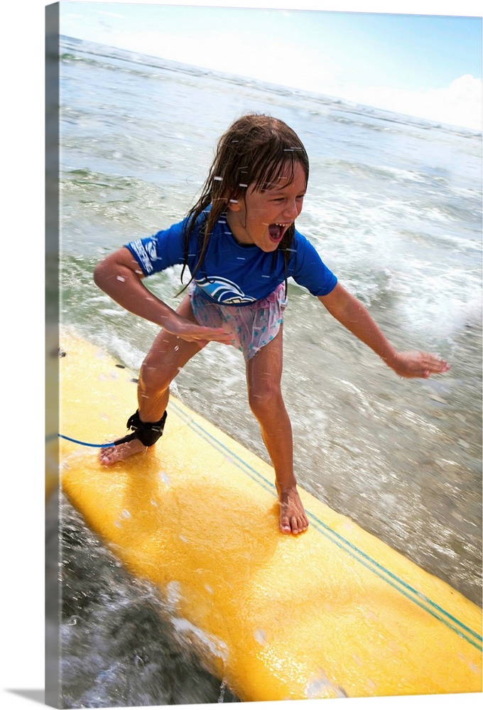 A young girl on a yellow surfboard, Gold Coast, Queensland, Australia