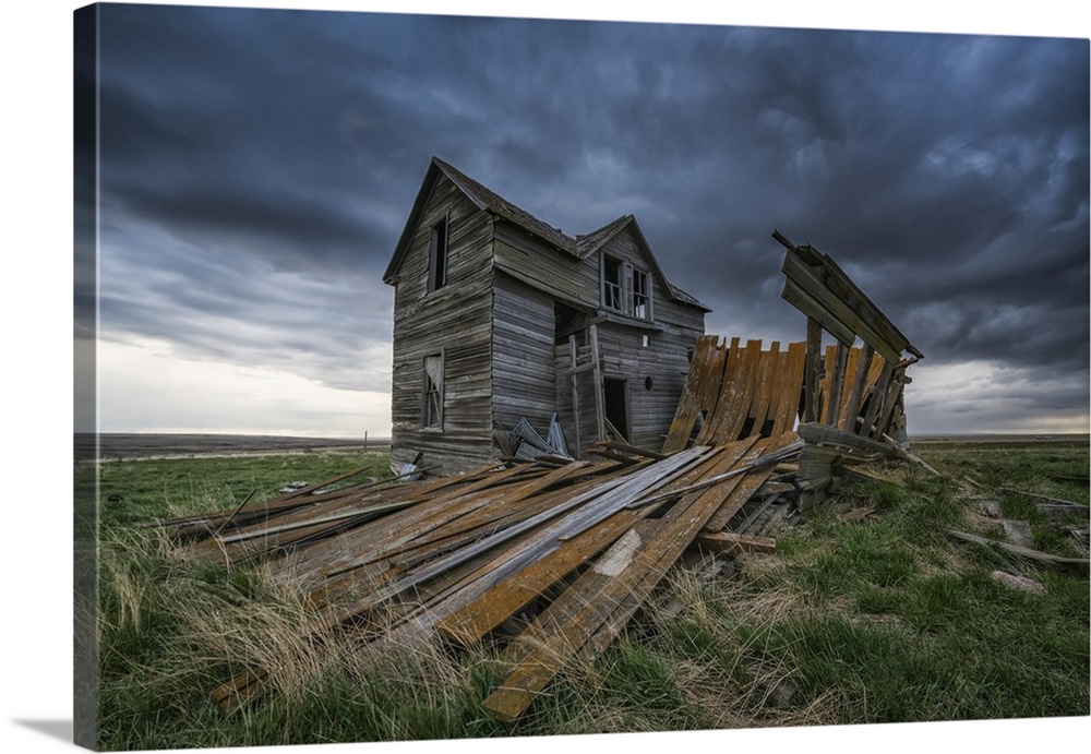 Abandoned house on the prairies with storm clouds overhead at sunset; Val Marie, Saskatchewan, Canada