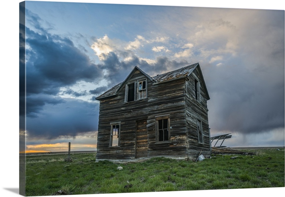 Abandoned house on the prairies with storm clouds overhead at sunset; Val Marie, Saskatchewan, Canada