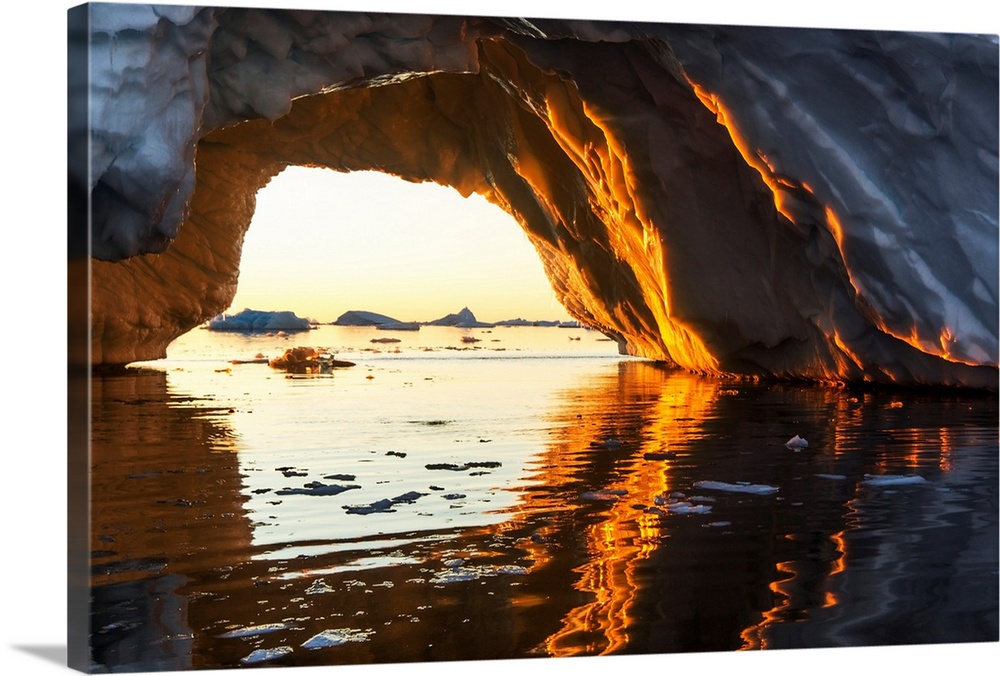 Antarctica, Petermann Island, Midnight sun shines through arched iceberg near Lemaire Channel.