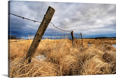 Barbed Wire Fence Posts With Dark Sky In Background, Alberta, Canada