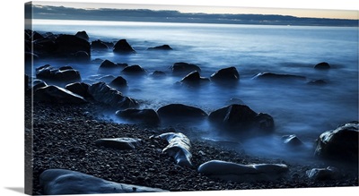 Beautiful blue misty ocean washing in against rocks on a West Coast beach; New Zealand