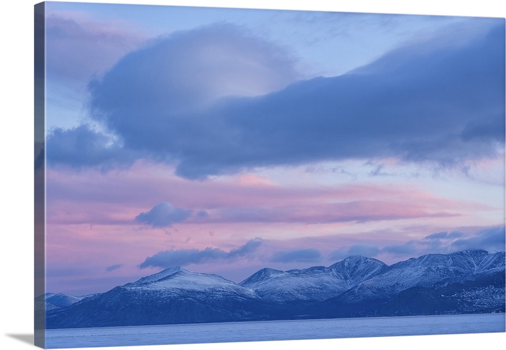 Beautiful sky over Kluane Lake as sunlight illuminates the clouds above the frozen water. A peaceful and serene scene from...