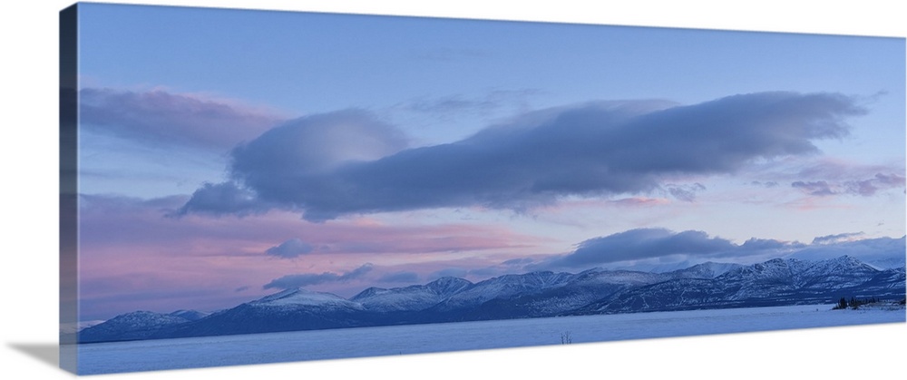 Beautiful sky over Kluane Lake as sunlight illuminates the clouds above the frozen water. A peaceful and serene scene from...