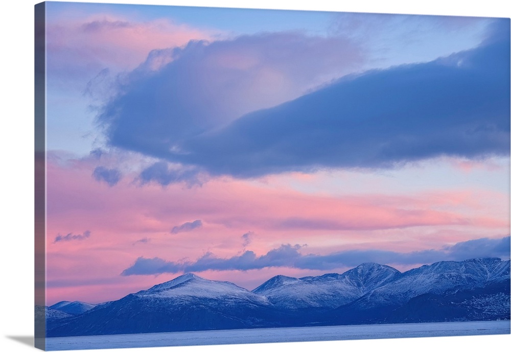 Beautiful sky over Kluane Lake as sunlight illuminates the clouds above the frozen water. A peaceful and serene scene from...