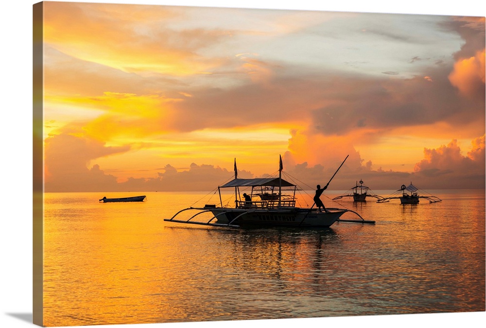 Beautiful sunrise in Alona Beach, a man moving his boat to reach the shore with a long stick, Panglao Island, Bohol, Phili...