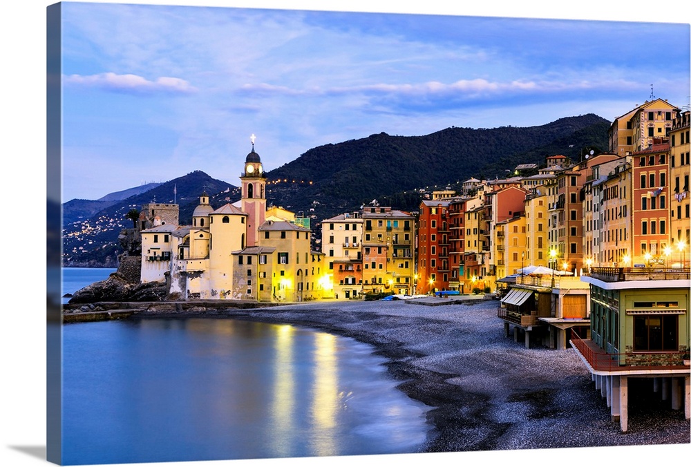 Buildings illuminated by lights along the water's edge at sunrise, Camogli, Liguria, Italy.