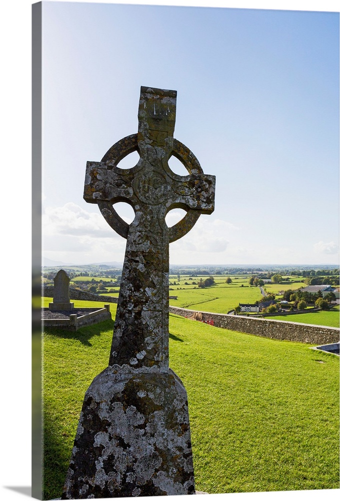 Celtic cross on grassy hill with stone wall under blue sky, Cashel, County Tipperary, Ireland.